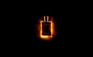 Black perfume bottle with black backround and light shining through from behind