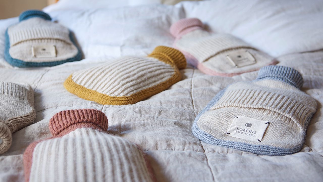 Hottie hot water bottle range in several colourways laid out on bed