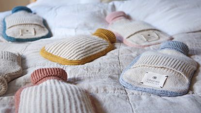 Hottie hot water bottle range in several colourways laid out on bed