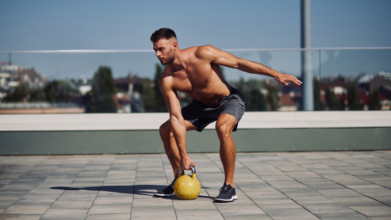 Man performing kettlebell swings outside