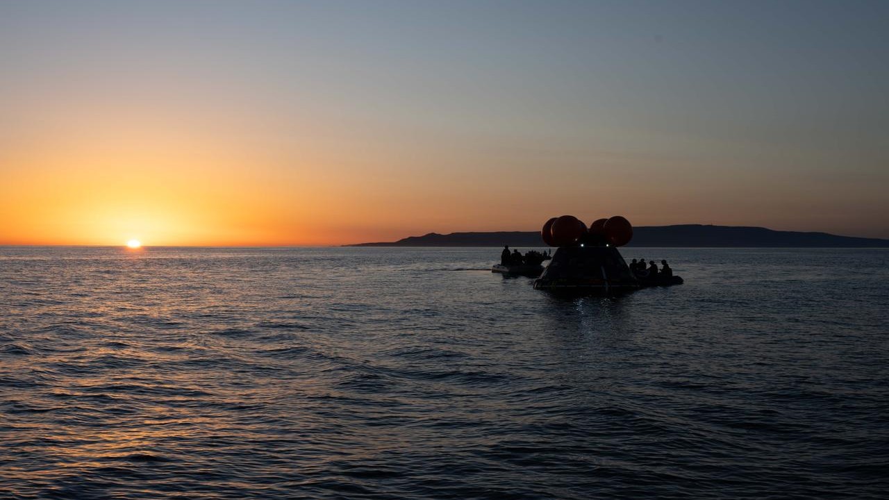 A mock Orion capsule floats in the ocean during sunset.
