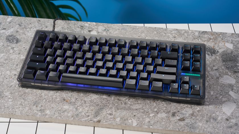 The Wooting 80HE in Ghost PCR case with black keycaps, on a stone surface with a blue background.