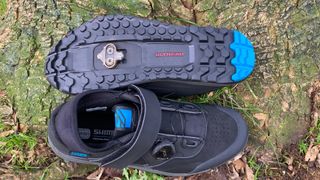 A pair of Shimano GE9 shoes with one upside down showing the sole