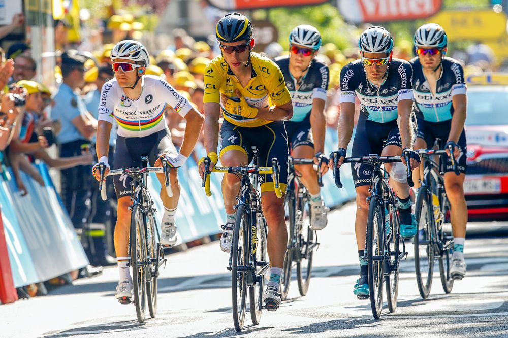 A battered Tony Martin crosses the finish line surrounded by teammates.