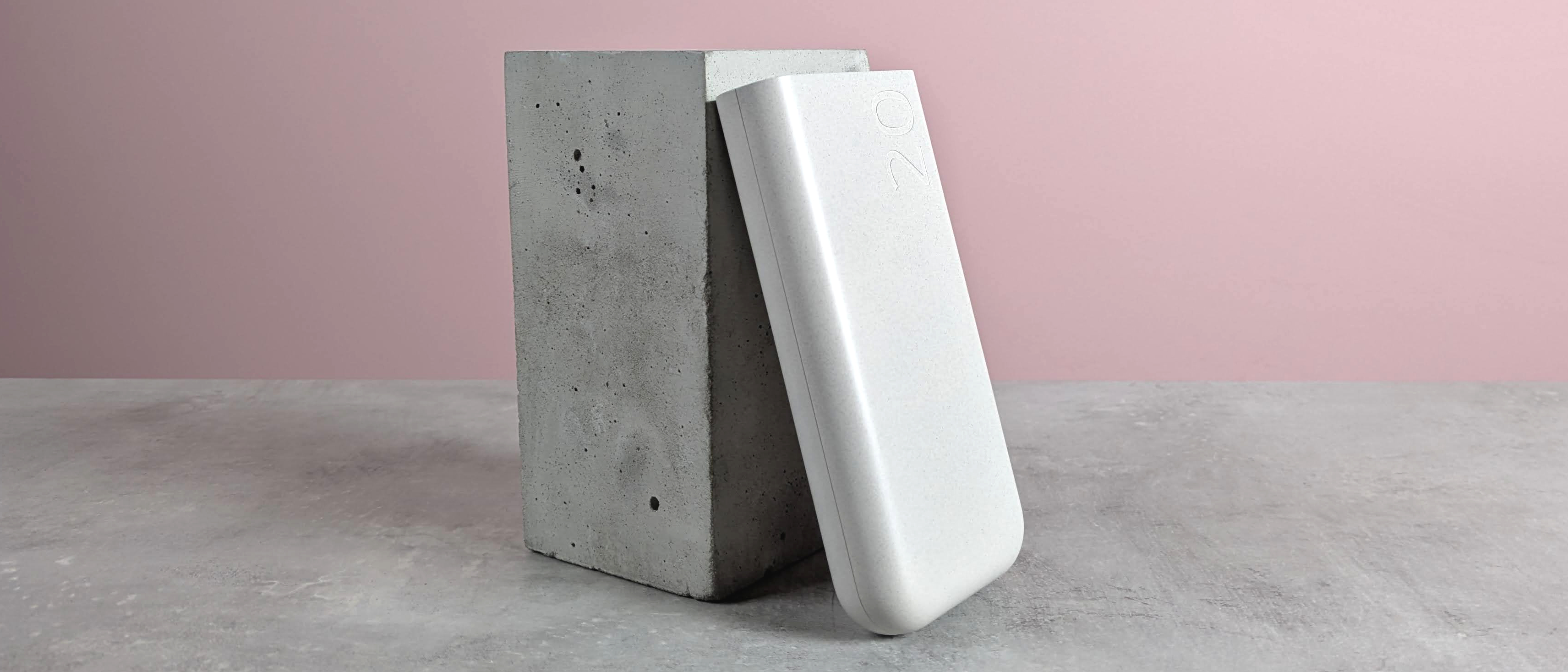 Samsung 45W 20000mAh Battery Pack leaning on plinth, on desk with pink background