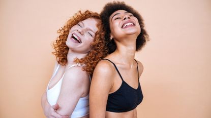 beauty image of two young women with different skin and body posing in studio for a body positive photoshooting. Mixed female models in lingerie on colored backgrounds