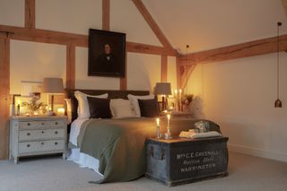 bedroom in oak frame house with oil painting and beamed walls