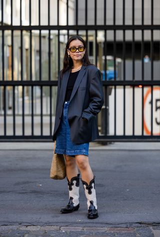 Woman wearing leather blazer over t-shirt with denim shorts and cowboy boots.