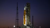 an orange rocket on a launch pad at sunset