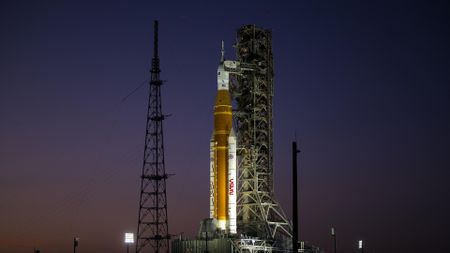 an orange rocket on a launch pad at sunset