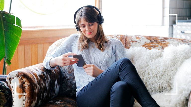 Woman listening to music via headphones sitting on the sofa, one of the best confidence boosters