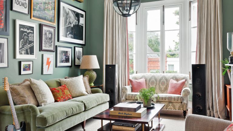 living room with green sofa and walls, colorful gallery wall, neutral sofa and chair and fireplace