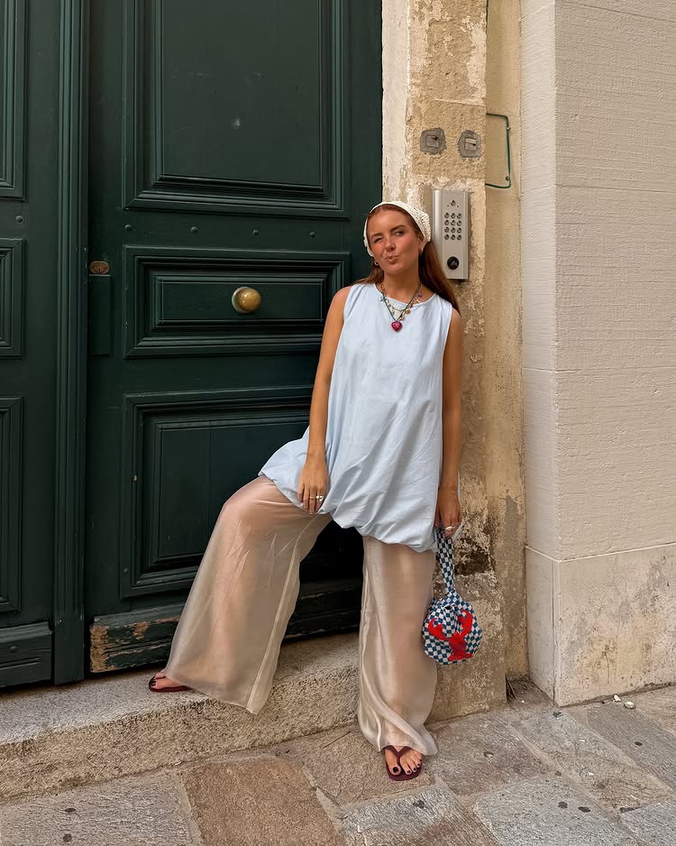 @rebeccaferrazwyatt wears a pair of sheer pink trousers with a long blue top and crochet head scarf