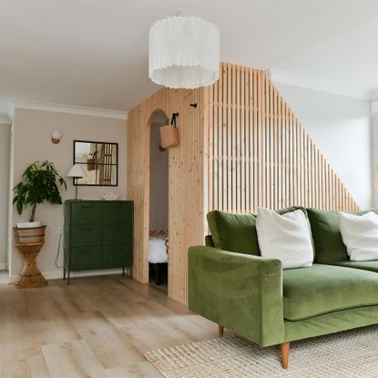 snug with green velvet sofa and slatted wall divider