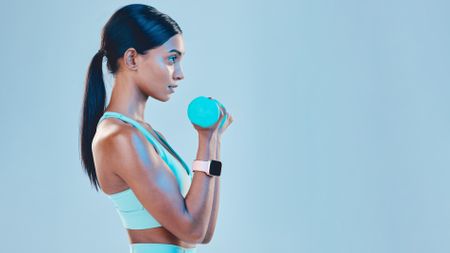 Woman facing side on to camera performing bicep curl with dumbbell