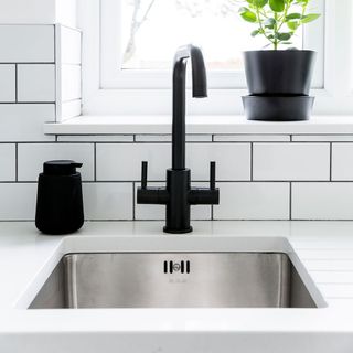 kitchen sink with white tiles and potted plant