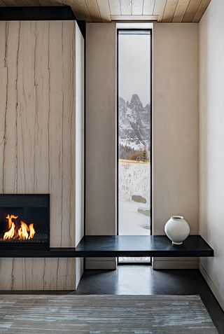 DNA Alpine interior with lit fire, and narrow window looking out to snowy landscape