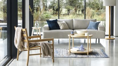 A cream sofa and wooden chair in a living area with glass walls