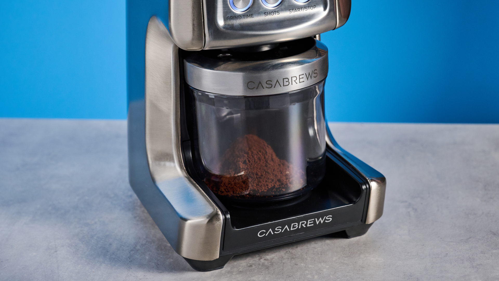 the casabrews tornado coffee grinder in silver showing the LED screen, grind adjustment dial, and photographed against a blue background