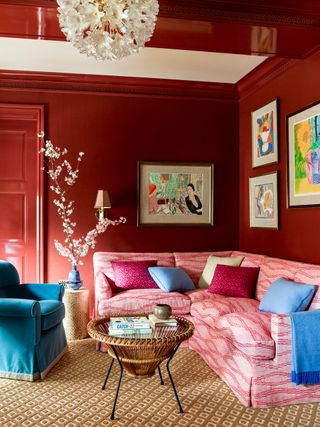 Red living room with pink sofa and blue vase, armchair and blanket