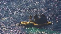 Astronauts L. Gordon Cooper Jr. and Charles Conrad Jr. exit their spacecraft after splashdown of the Gemini-5 spacecraft. They are photographed boarding a life raft with the help of Navy divers.