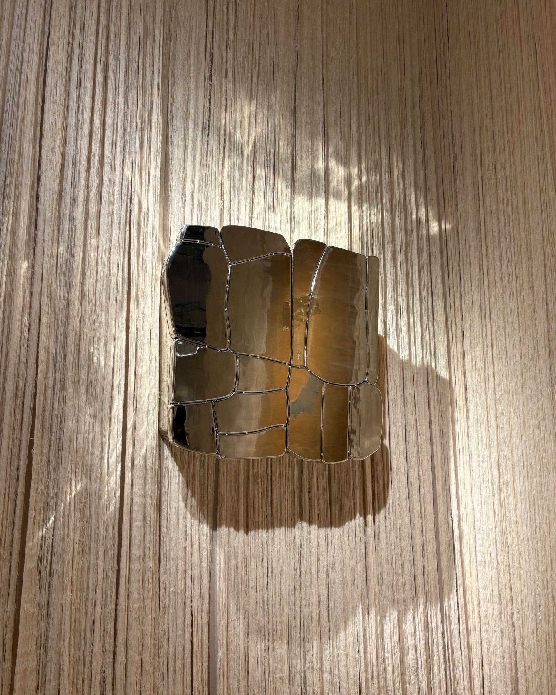 A series of contemporary furniture items with either a stitched-up or a tetris-looking structure sits in a warmly lit gallery space.