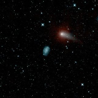 The Pan-Starrs comet is shown passing near a spiral galaxy.