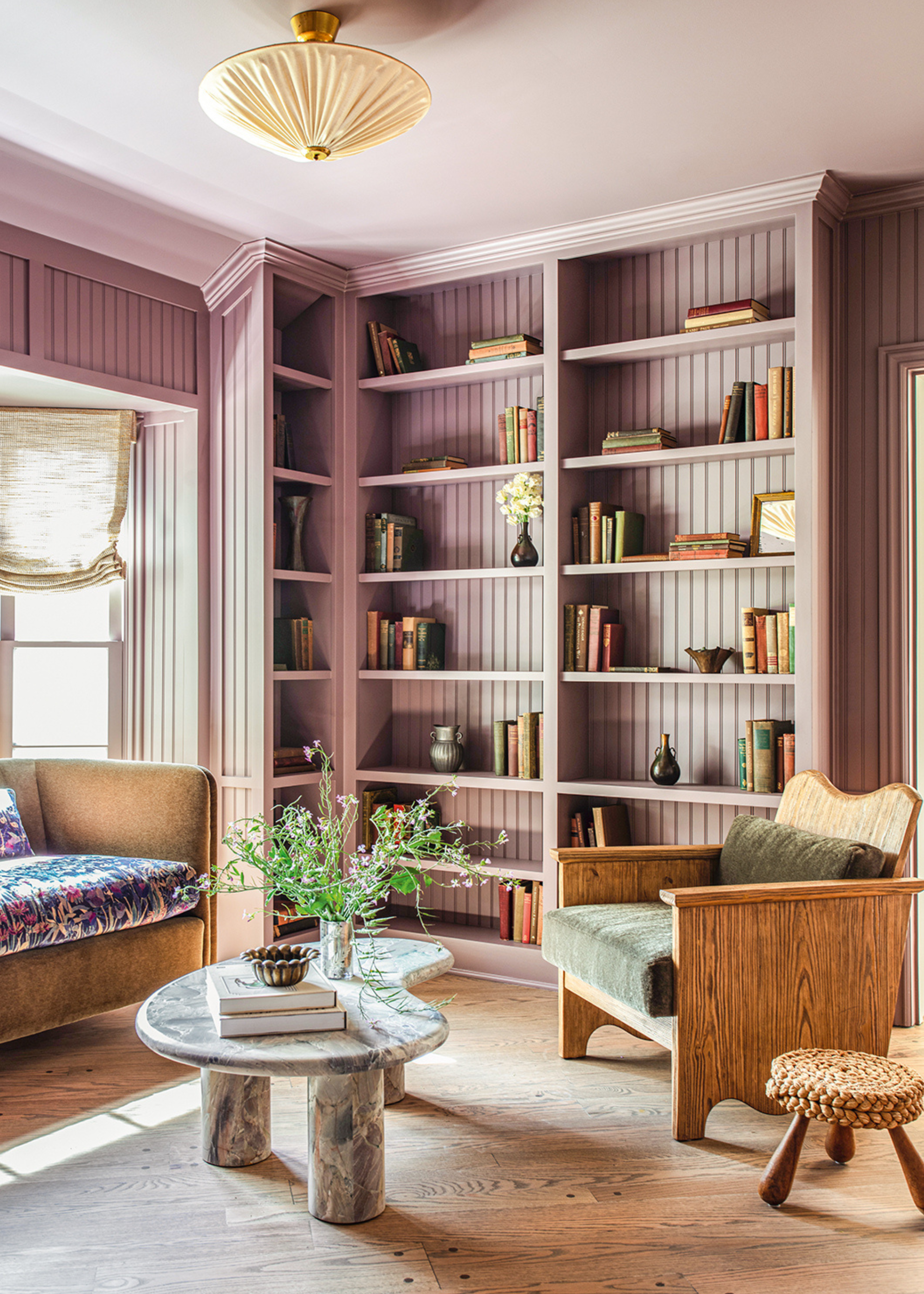 a living room with accent furniture pieces with built-in paneled wall-to-wall storage in lilac that is color drenched across the walls of the space