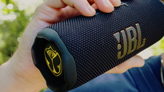A close-up of the JBL Flip 7 Tomorrowland speaker being held in someone's hand.