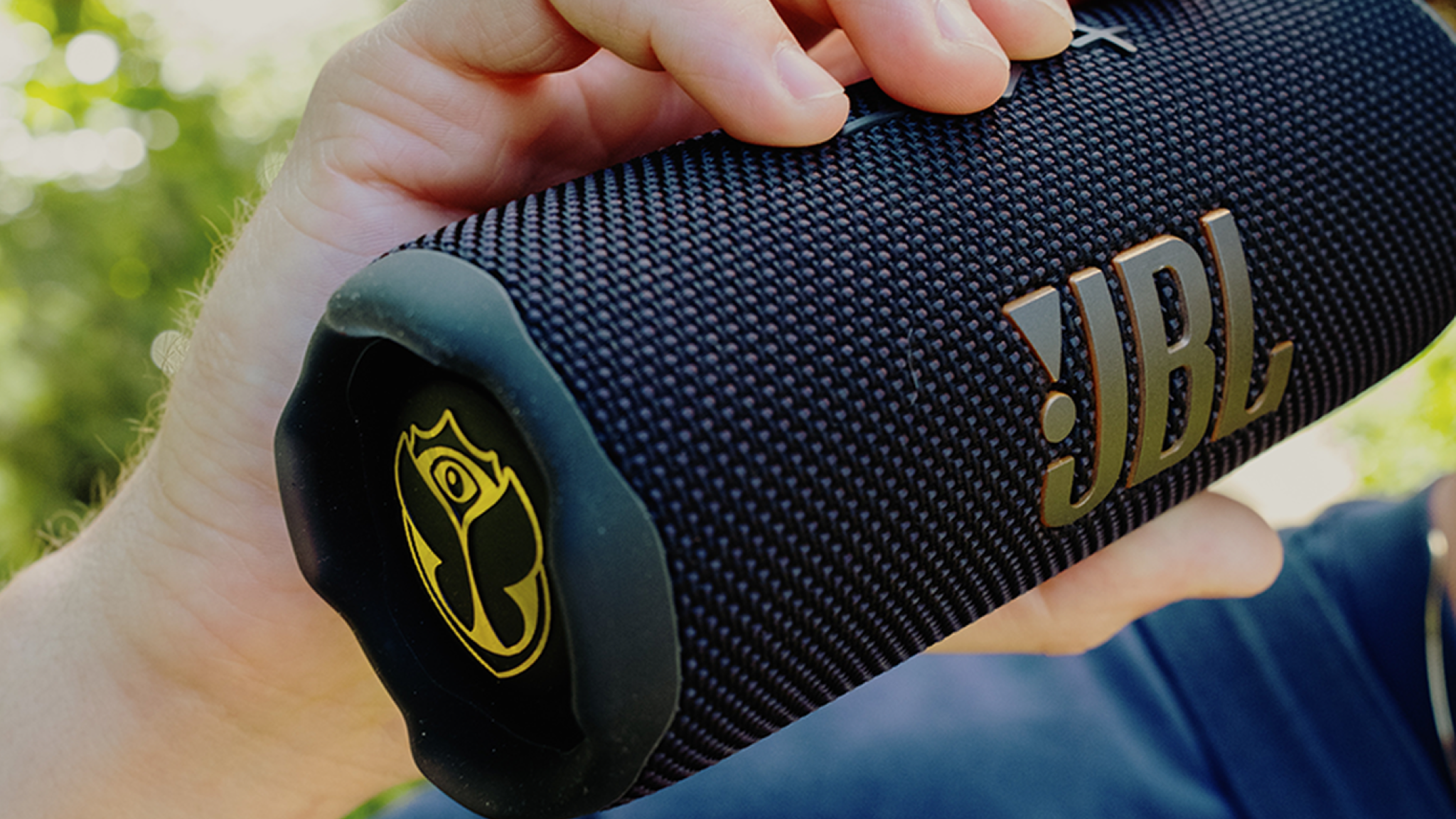 A close-up of the JBL Flip 7 Tomorrowland speaker being held in someone&#039;s hand.