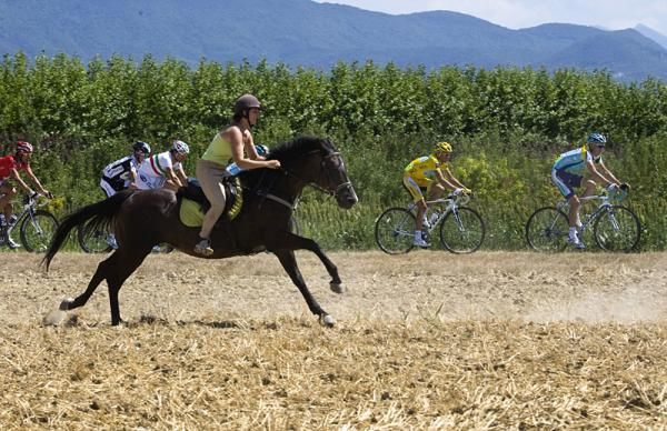 A fan on horseback races the maillot jaune.