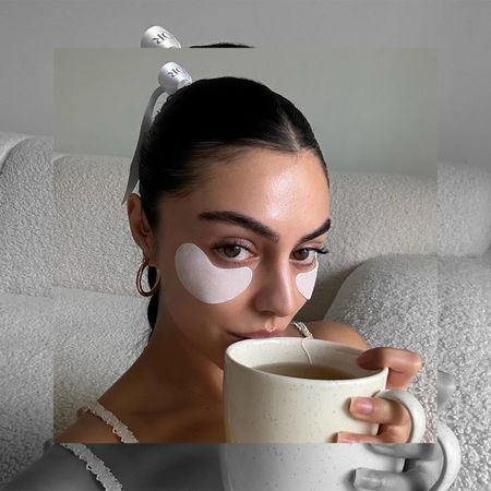 Woman wearing eye patches and drinking tea