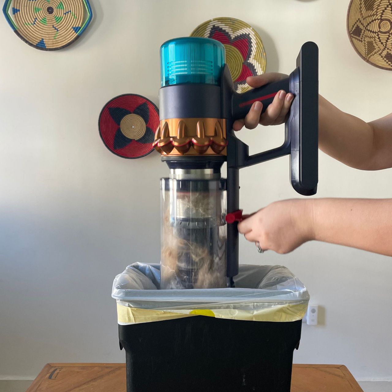 Emptying the dust canister of the Dyson Gen5detect over a small black dust bin