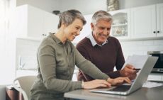 Laptop, budget and finance with a senior couple at a table in their home together for retirement planning. Computer, investment or savings with an elderly husband and wife accounting for the future