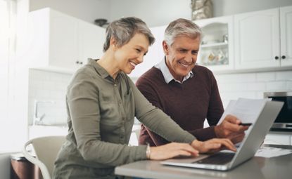 Laptop, budget and finance with a senior couple at a table in their home together for retirement planning. Computer, investment or savings with an elderly husband and wife accounting for the future
