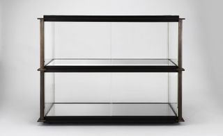 A bronze skeleton cabinet supported by blackened steel trays and strengthened ribbed glass panels