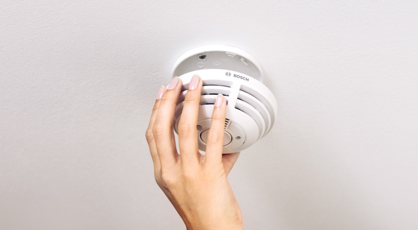 A Hand Adjusting a Smart Smoke Detector