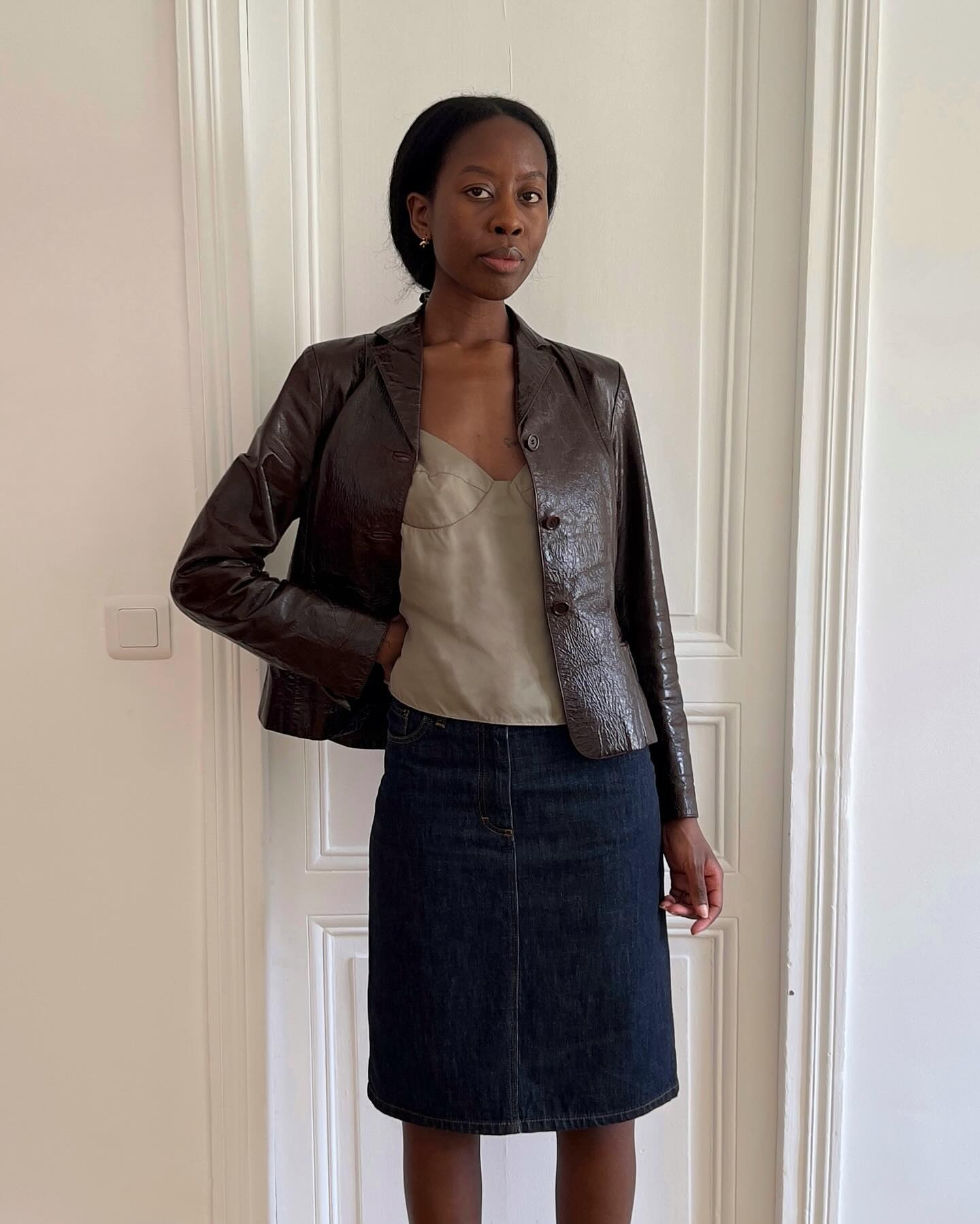 French woman wearing a brown leather jacket and dark denim knee skirt