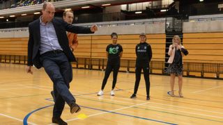 Prince William mid kick while playing football at the 10th Anniversary Celebration of Coach Core at Copper Box Arena on October 13, 2022 in London, England.
