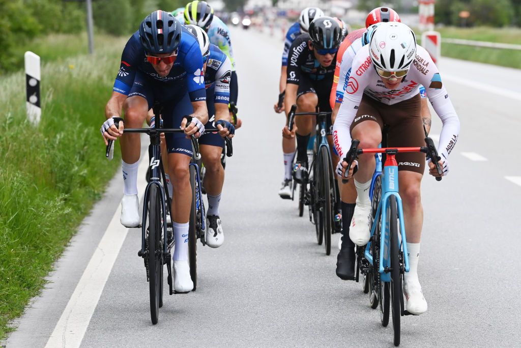 Overall leader INEOS Grenadiers's British rider Geraint Thomas (C) and fellow teammates cycle under the rain on stage 14