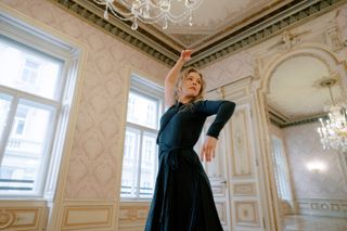 A blonde woman wearing a black dress dances inside a room at Almanac Palais Vienna