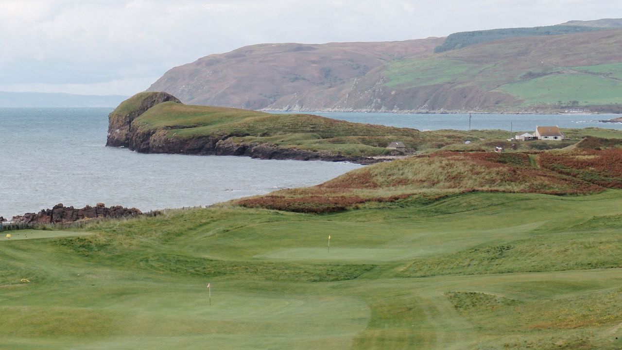 A hole at Dunaverty Golf Club with the sea behind it