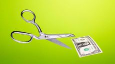 Stainless steel scissors in mid air about to cut US $1 dollar bill over gradated green background