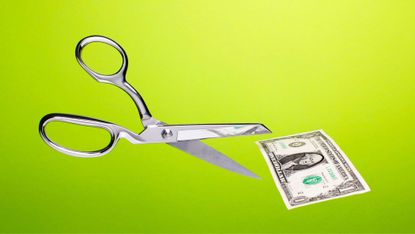 Stainless steel scissors in mid air about to cut US $1 dollar bill over gradated green background