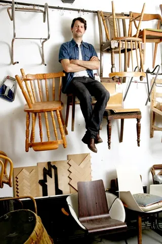 Martino Gamper on chair hung on wall