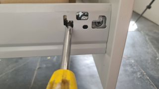 Making adjustments to a kitchen drawer with a screwdriver