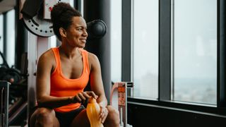 Woman sitting on bench at the gym, holding a water bottle