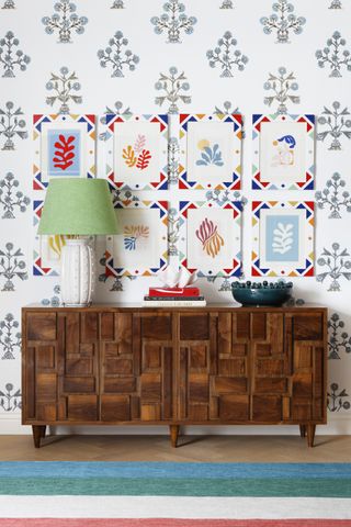 Wooden sideboard with bold wallpaper and gallery wall