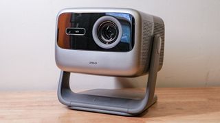 A JMGO N1S Ultimate projector on a wooden table top.