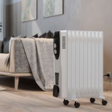 Oil-filled radiator in living room next to a sofa with a blanket over the arm